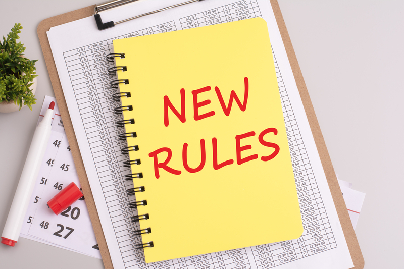 A notebook atop papers with the text 'New Rules' displayed in red marker.