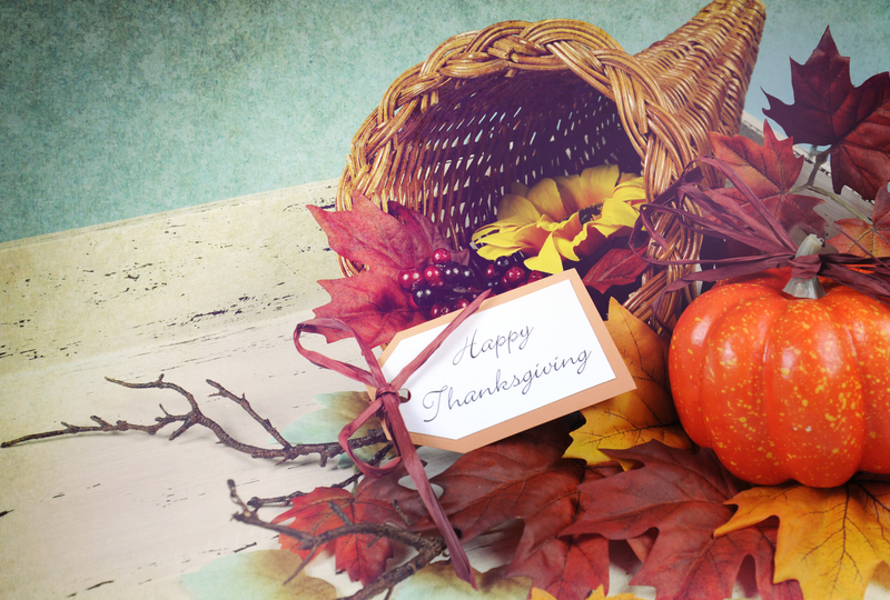 Happy Thanksgiving cornucopia with Autumn Fall leaves, pumpkin, sunflower and berries on white shabby chic tray against a pale blue background, with retro grunge filter. 